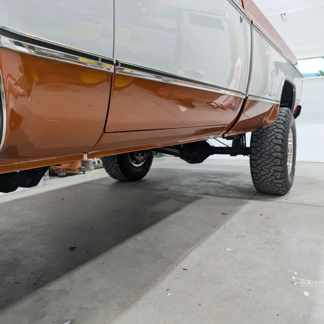 Orange and white square-body Chevy pickup with clear film on the rockers